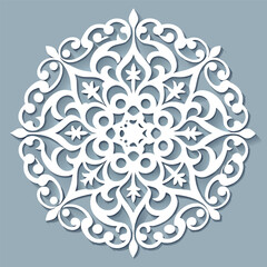 Intricate white paper cut-out design with symmetrical floral and ornamental patterns on a gray background.