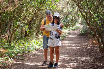 Obraz premium Carefree couple of senior man and woman in a trekking day in the forest enjoying nature and healthy lifestyle in outdoors, travel, vacation or retirement