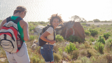 Two Female Friends With Backpacks On Vacation On Hike Through Countryside On Coastal Path