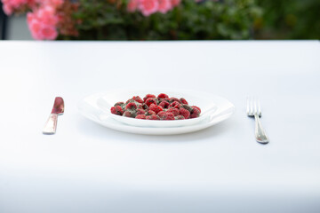 Dish of raspberries covered with mold placed with fork and knife on a dining setup.