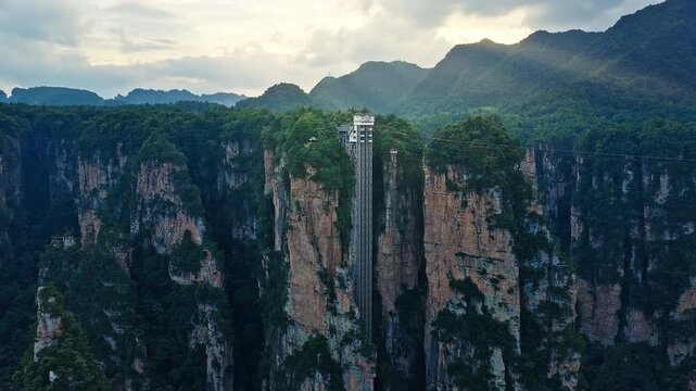 Unique outdoor glass elevator built on a sheer cliff among spectacular quartz-sandstone pillars in Hunan. majestic Zhangjiajie national forest park, Wulingyuan Scenic Area in China. 