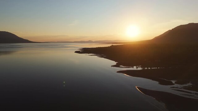 Sunset glows over the Putorana Plateau as mirror water and curved sandbanks lead the eye along Lake Lama. Warm light, clean horizon and minimal ripples make perfect tourism and drone scenery
