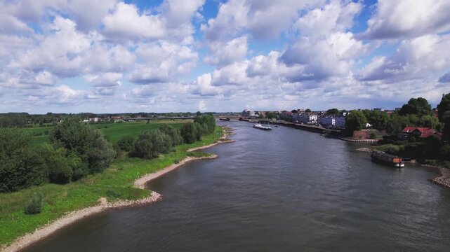 River IJssel passing Zutphen countenance seen from above against a blue vibrant colourful sky with IJsselkade quay and recreational port entrance visible in low water level
