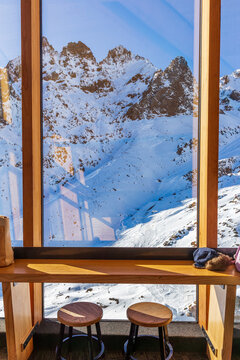 Snow-covered alpine peaks are framed by tall timber windows