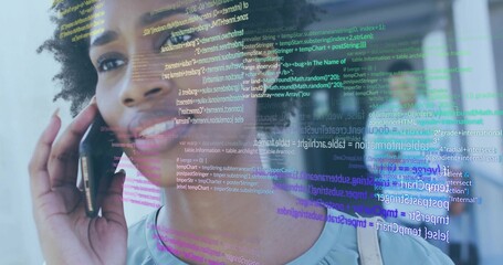 Woman carrying shoulder bag holding smartphone at ear in office corridor, with code snippets