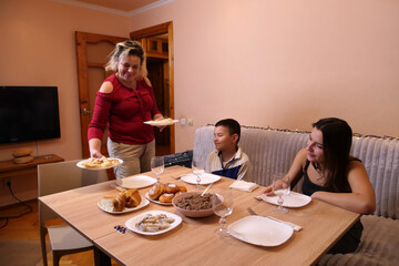 Woman sets plates with dishes on table during family holiday celebration.