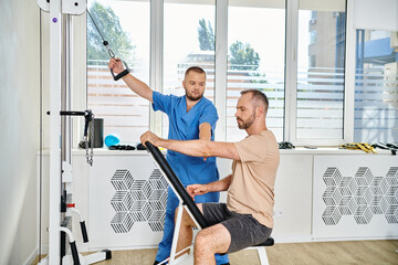 Obraz premium Man working with his physiatrist in a rehabilitation session at a modern facility