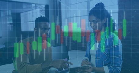 Collaborating professionals analyzing candlestick chart at office table, with tablet and monitors