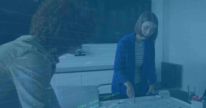Reviewing two architects examining blueprint in meeting room, with charts on display