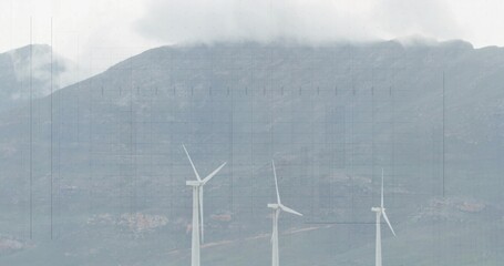 Standing three wind turbines rotating blades on mountain hillside, with clouds and rocky ground