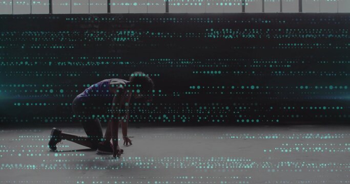 Kneeling sprinter wearing number jersey in studio, running shoes powering start, data overlay