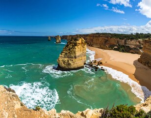 Coastal panorama of dramatic rock formations, turquoise water, and a sandy beach under a vibrant blue sky