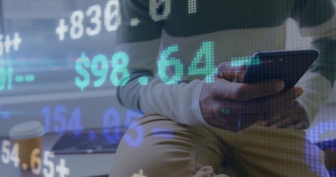 Man in sweater using smartphone in office lounge, reviewing stock data with digital overlays