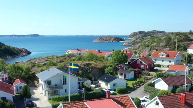Swedish coast and Sweden flag on red white wooden summer houses by the sea. Blue ocean on a sunny day in summer. Beautiful dream vacation in clean environment