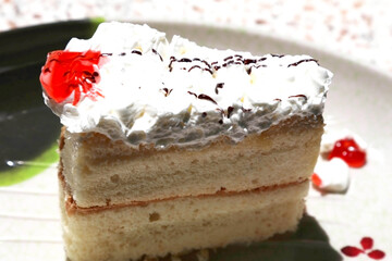 Three layer cake glazed with whipped cream Top with jam and chocolate. Placed side by side in a plate