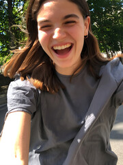 Young woman joyfully riding a bicycle through a sunny park on a warm day, showing excitement and freedom