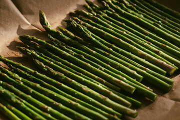 Fresh asparagus spears arranged on parchment ready for roasting in a warm kitchen in a cozy kitchen...