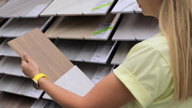 Hands holding ceramic tiles in hardware store comparing options for renovation