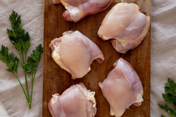 Raw Organic Boneless Skinless Chicken Thighs on a Wooden Board, top view.