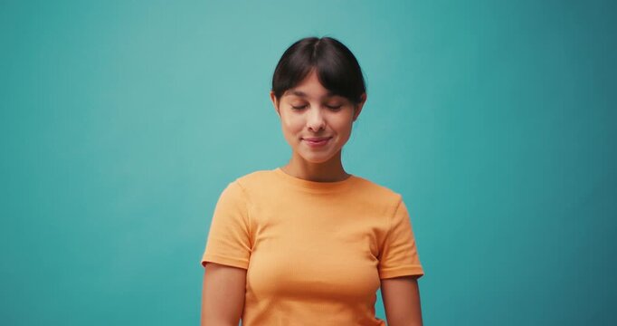 Hispanic woman looks from side to side on blue background