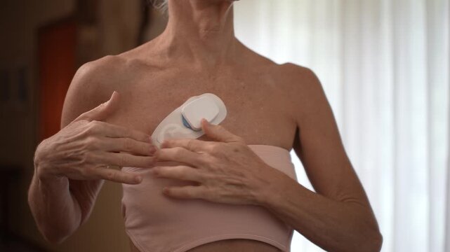 A mature adult applies a heart monitor to track heart rate and detect atrial fibrillation. Monitoring is crucial for maintaining health and well-being.