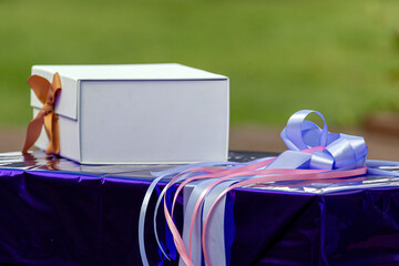 Gift box and decorative ribbons on a table in a garden during a sunny day