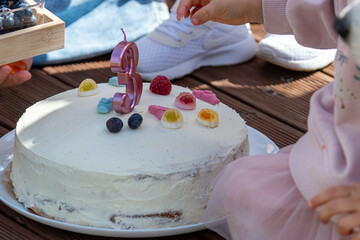 Colorful birthday cake with fruit toppings and a candle during a celebration
