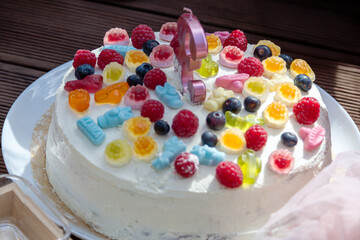 Colorful birthday cake decorated with sweets and fruit at an outdoor celebration
