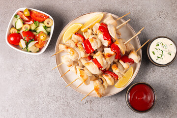 Grilled chicken skewers. Satay with side lemon and salad. Kebab with sauces. 