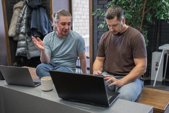 Programmers discussing over laptop working at startup. Office, business and friends together in teamwork with notebook, laptop and coffee workplace