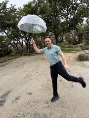 Happy Man Posing Playfully with an Umbrella on a rainy day
