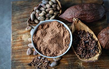 Top view of cocoa powder with cocoa bean and cocoa nibs, cacao pods on gray background