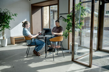 Programmers discussing over laptop working at startup. Office, business and friends together in teamwork with notebook, laptop and coffee workplace