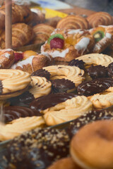 Wide view of bakery glass display showcasing assorted pastries, from donuts and twists to croissants, highlighting fresh baked goods and inviting café atmosphere.