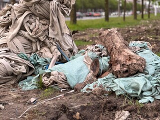 Piles of construction waste and old fabric rags with logs lying on the ground in an urban area, environmental pollution and urban trash problem, waste disposal and recycling theme.