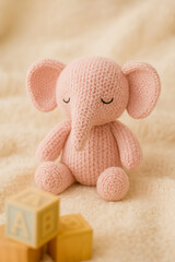 Charming knitted pink elephant plush toy with alphabet blocks on a soft, warm, beige background, evoking warmth and childhood nostalgia.