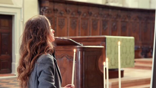 Woman holding lit candle inside historic church Chalon sur Saone France