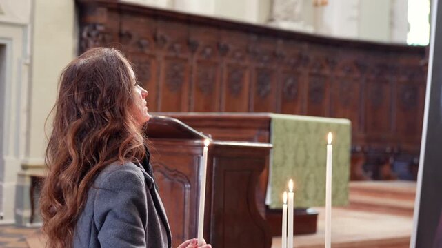 Woman holding lit candle in historic church interior Chalon sur Saone France