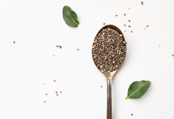 Chia seeds in old metal spoon on light gray background flat lay top view. Food background, healthy...