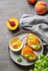 Toast bruschetta with peach, nectarine, cream cheese or ricotta and honey on a plate on a dark background