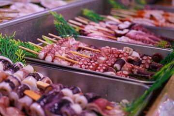 Raw Octopus Tentacles on Skewers at Fish Market. Fresh Seafood Street Food