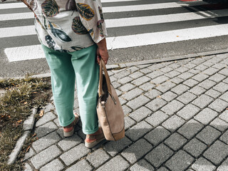 Elderly women crossing pedestrian crosswalk in city, close-up view of legs and shoes on zebra crossing symbolizing urban lifestyle, mobility and safety