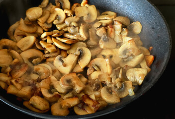 Golden sautéed mushrooms cooking in a pan, releasing steam and rich aroma.