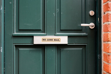Sign on green door discouraging unwanted advertisements and promotional materials in residential...