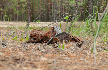 Rusty metal debris lies on barren ground, surrounded by scattered fallen leaves. The scene evokes a...