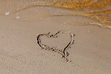 drawing a heart in the sand on the river bank