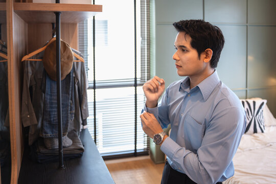 Get dress, asian young man, business man standing wearing shirt, female getting dressed preparing before go to work looking reflection in the mirror in the morning at home.