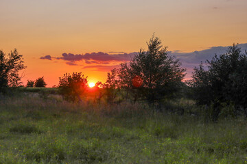 This shot captures a magical sunset as the fiery sun dips below the horizon, painting the sky in...