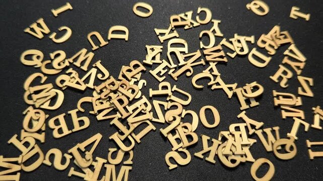 A pile of small wooden alphabet letters randomly scattered across a dark textured background, with other letters falling over them.
