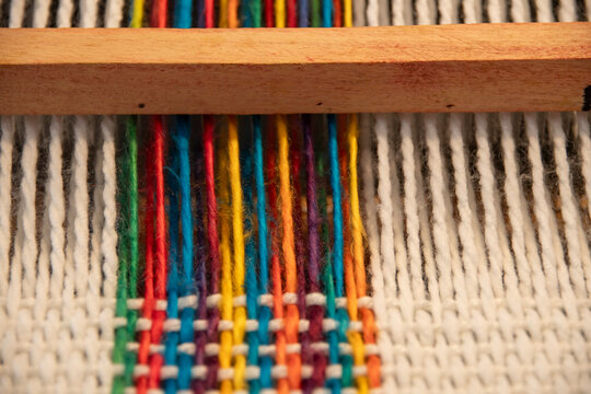 Trama de lanas de colores y blancas en telar Mar&iacute;a, con textura de trama, relleno el encuadre, primer plano macro, desenfoque selectivo